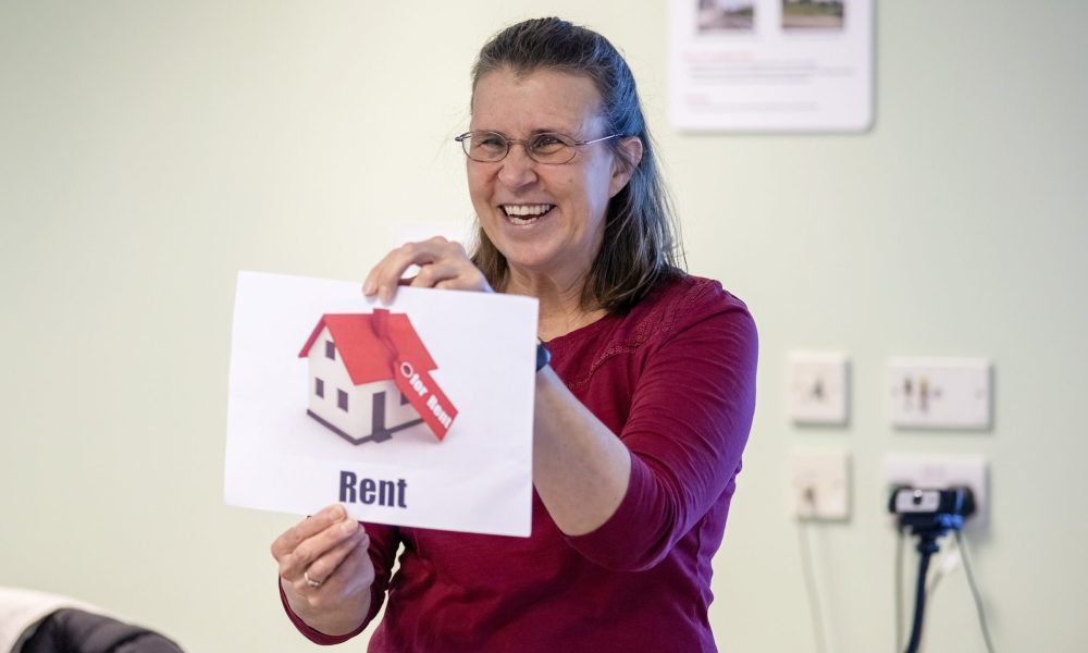 A female workshop leader holding up a card with a house and the word rent on it